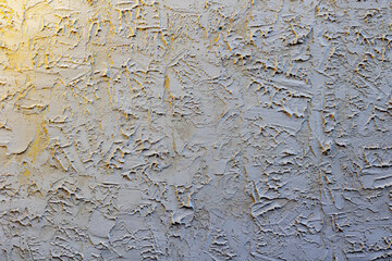 Textured white plaster wall with abstract patterns and yellow tint