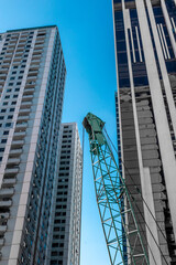Urban construction scene with crane and skyscrapers against blue sky