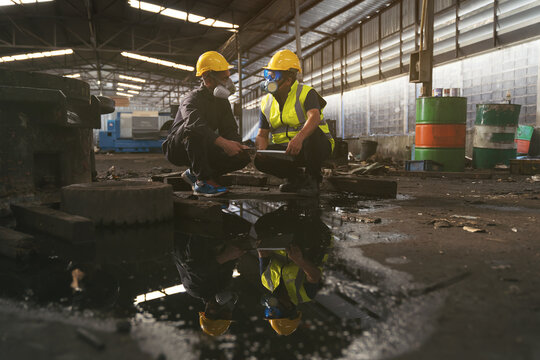 Liquid flowing in the factory. Chemical leak and safety first concept. Group of chemical specialist wear safety uniform, gas mask inspecting chemical leak in industry factory