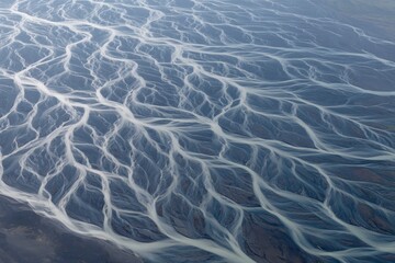 Fototapeta premium Aerial view of braided river system with pale streams across a dark silted landscape