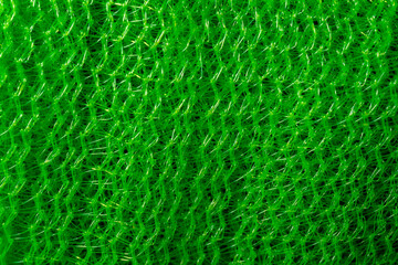Close-up of a vibrant green mesh pattern, creating an abstract, textured plastic surface.