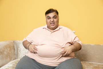 Obesity - Unhappy overweight indian man have problem with big belly fat. Plus size asian guy suffer from indigestion or gastric problem.