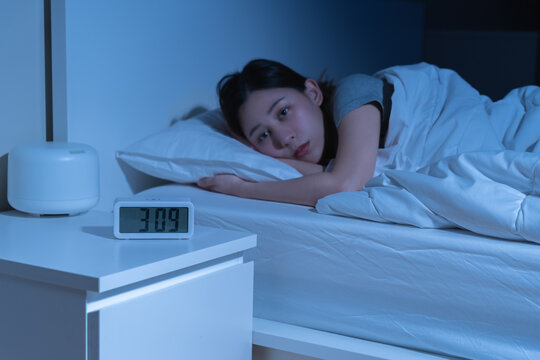 Annoyed, stressed, anxiety asian young woman suffering from insomnia, frustrated awake on bed at night, headache or migraine, health care problem, disturbed trouble of loud noise, unable sleepless.