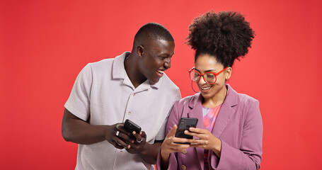Happy couple, funny or meme with phone in studio for social media or fashion on red background....