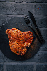T-bone grilled beef steak with spices on black serving plate