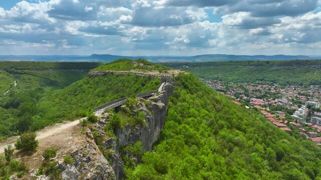 Winding Path On Steep Forested Hillside Towards Ancient Ovech Fortress Overlooking Town Of Provadia In Bulgaria. wide drone shot
