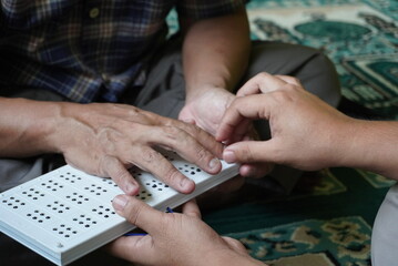 Hands gently interact with a Braille device, symbolizing accessible education and supportive...