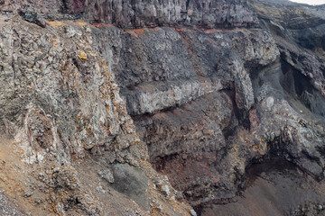 Close-up view of the rocks on the rim and inner slope of the volcanic crater. Majestic mountain landscape. Layers of rocks in the crater of a volcano. Rough stone texture. Great natural background.