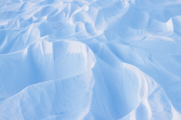 Snow texture. Wind sculpted patterns on snow surface. Wind in the tundra and in the mountains on the surface of the snow sculpts patterns and ridges (sastrugi). Arctic, Polar region. Winter background