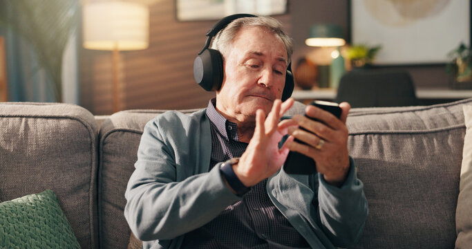 Senior man, phone and listening to music with headphones on sofa for online streaming at home. Elderly, male person or user with mobile smartphone for podcast, radio news or entertainment at house