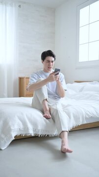 寝起きに不穏なメールやチャットを見てしまう若い男性　仕事困るや株や投資の下落などの落ち込むネガティブイメージの縦動画