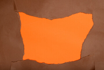 A bold orange backdrop framed by irregularly torn edges of deep brown paper