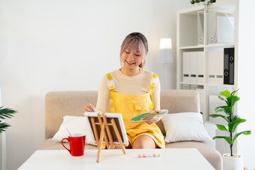 Inspired teen girl with brush and palette painting, smiling in home interior. Creative girl enjoying her new hobby, painting still life, Teenagers lifestyle concept.
