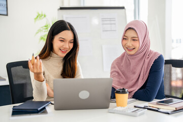 Multiracial young female employees work on laptop discuss business cooperation ideas at meeting...