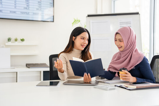 Teamwork process. Successful colleagues work and discuss their goals and plans together in an modern office meeting room. Multiracial smile happily while working together in a professional setting.