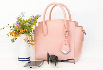 pink hand bag, mobile phone and sunglasses accessories of lifestyle woman arrangement flat lay style on background white