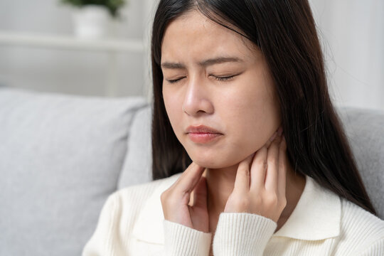 Asian woman put on neck due to a sore throat. female tonsillitis causes a inflammation. treated by taking water, taking antibiotics, consult a doctor, virus, corona virus, Influenza, flu