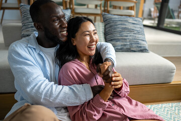 Young diverse multiethnic couple moving in new home. Couple is having fun in new house at moving day