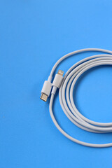 Cable with Type-C connector insulated, charging cable coiled on a blue background.