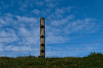 An electric fence against a cloudy blue sky