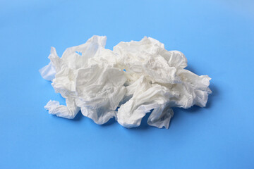 Used crumpled tissues scattered on a blue surface.