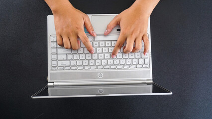 Top view of a man hands typing on laptop keyboard isolated on black background