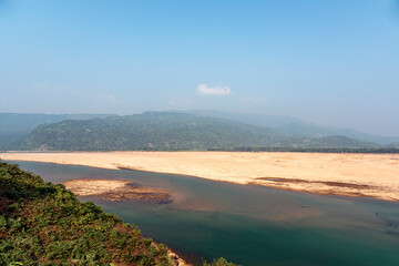 Serene River Landscape with Sandy Banks, Rolling Hills, and Vegetation under Clear Sky