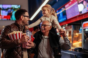 Cheerful family in movie theater hall.