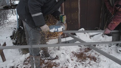 A skilled worker fabricates metal in harsh snowy conditions, showcasing expertise in winter metalworking