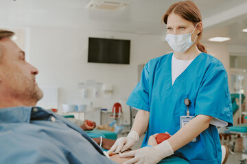 Caucasian middle aged female nurse wearing medical mask assisting Caucasian middle aged man...