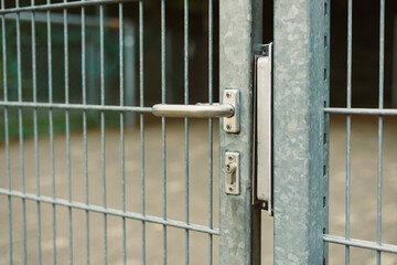 A detailed closeup view of an open metal gate showcases its simple lock mechanism, situated within...