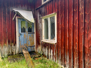 Wooden cottage in bad condition with a blue door