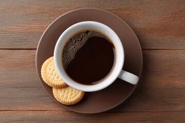 Top view of coffee cup on saucer next to two biscuits on wood