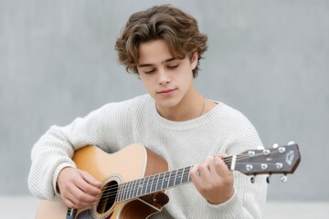 Young man with wavy hair playing an acoustic guitar