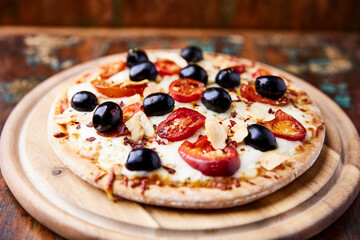 Pizza with salami and mozzarella cheese, jalapeno pepper and black olives. Wooden background. Soft focus. Close up.	
