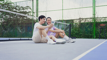 Couple enjoying moments on a pickleball court while discussing strategies in the late afternoon