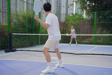 Engaging pickleball match between two players in a modern urban setting surrounded by greenery...