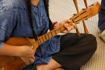 Selective focus is on a Thai musical instrument that resembles a guitar, but it's actually called a pin, a traditional Thai musical instrument made of wood.