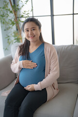 Pregnant asian woman holds hands on belly touching her baby caring about her health Beautiful happy...