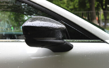 Close up stock photo of water drops on the glossy plastic cover of the car's side mirror
