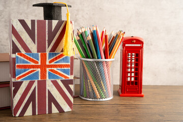 UK flag with graduate hat on english language book.