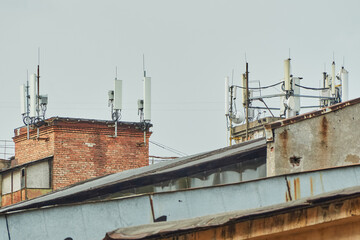 Multiple cellular antennas and communication towers on industrial building rooftops under an...