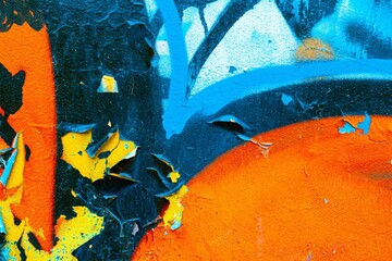 Abstract texture with vibrant blue, orange, yellow hues reminiscent of 80s graffiti art. Distressed, peeling paint surface, textured look. Posters, backgrounds, digital art, retro 80s, modern visuals