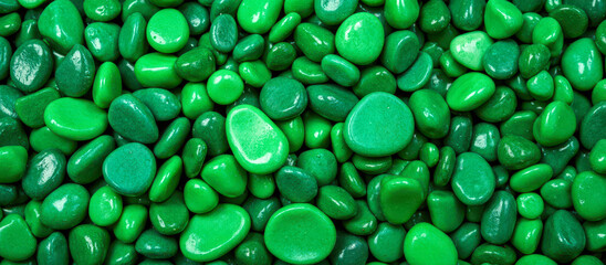 Macro background texture of small wet green pebbles, beautiful abstract pattern of smooth, glossy and very shiny decorative stones