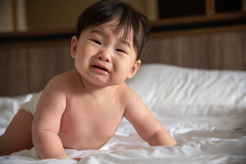 A crying Asian baby on the bed of six months has woken up and is calling for her mother