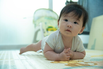 Adorable Baby laying on stomach developing neck control .tummy time for strengthen baby neck and shoulder muscles. Cute infant lying crawling on white bed happiness and fun. Tummy Time Concep
