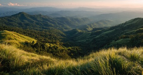 Panoramic sunset view of rolling green hills and valleys, showcasing layers of mountains under a soft, hazy sky