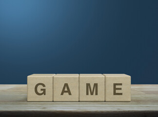 Game letter on wood block cubes on wooden table over light blue wall, Leisure and education concept