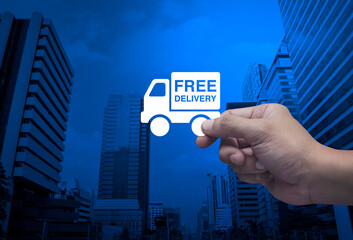 Hand holding free delivery truck flat icon in fingers over modern office city tower and skyscraper, Business transportation service concept