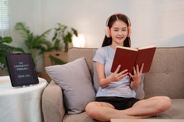 Asian young woman embracing longevity lifestyle reading book and listening to health wellness...
